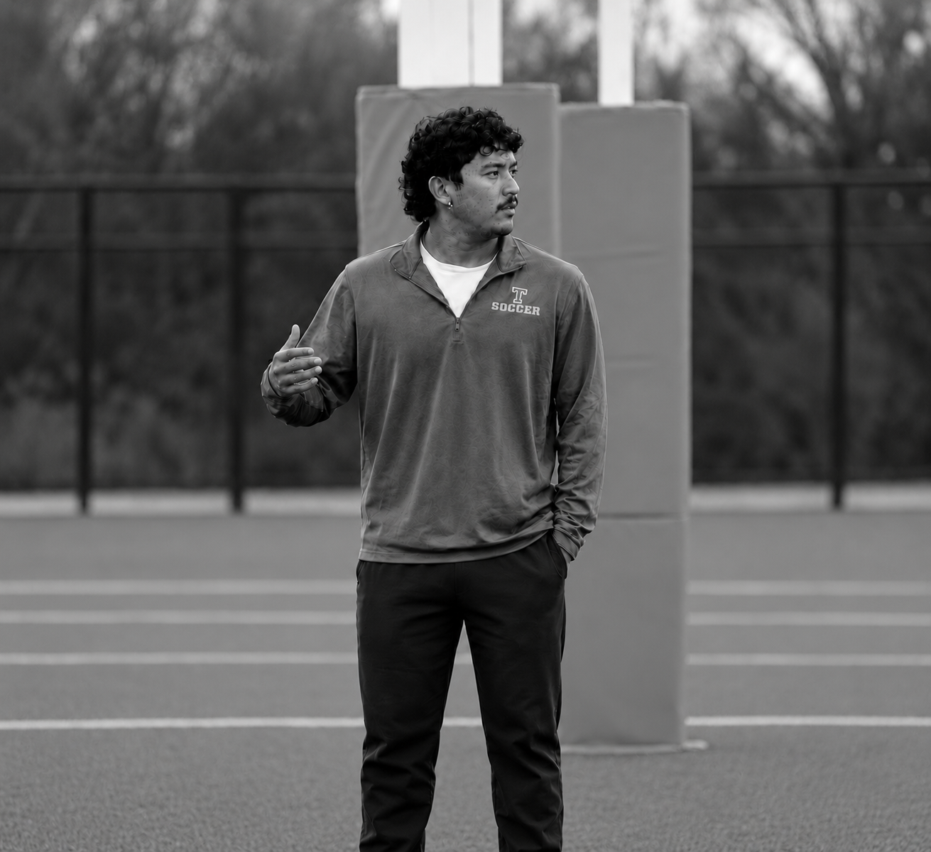 A soccer coach standing on the field mid-instruction